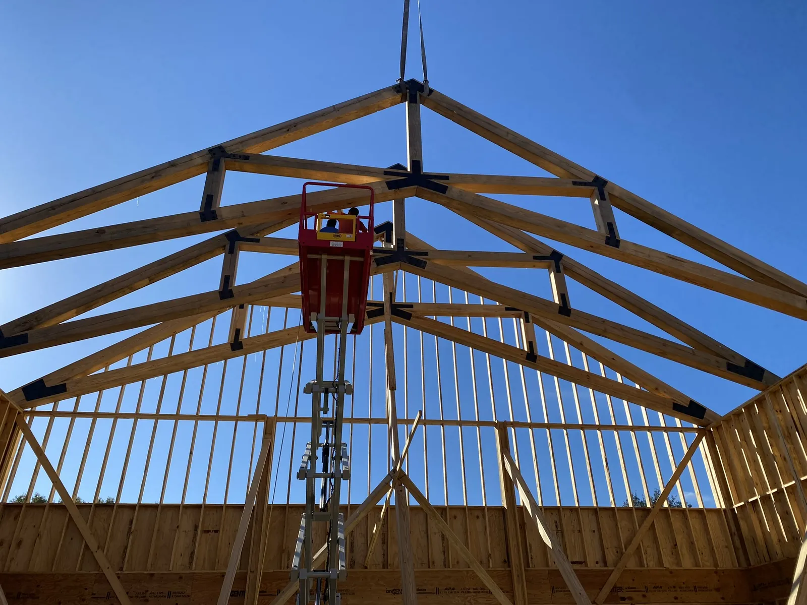 Roof trusses set in place during framing, seen from below against a blue sky