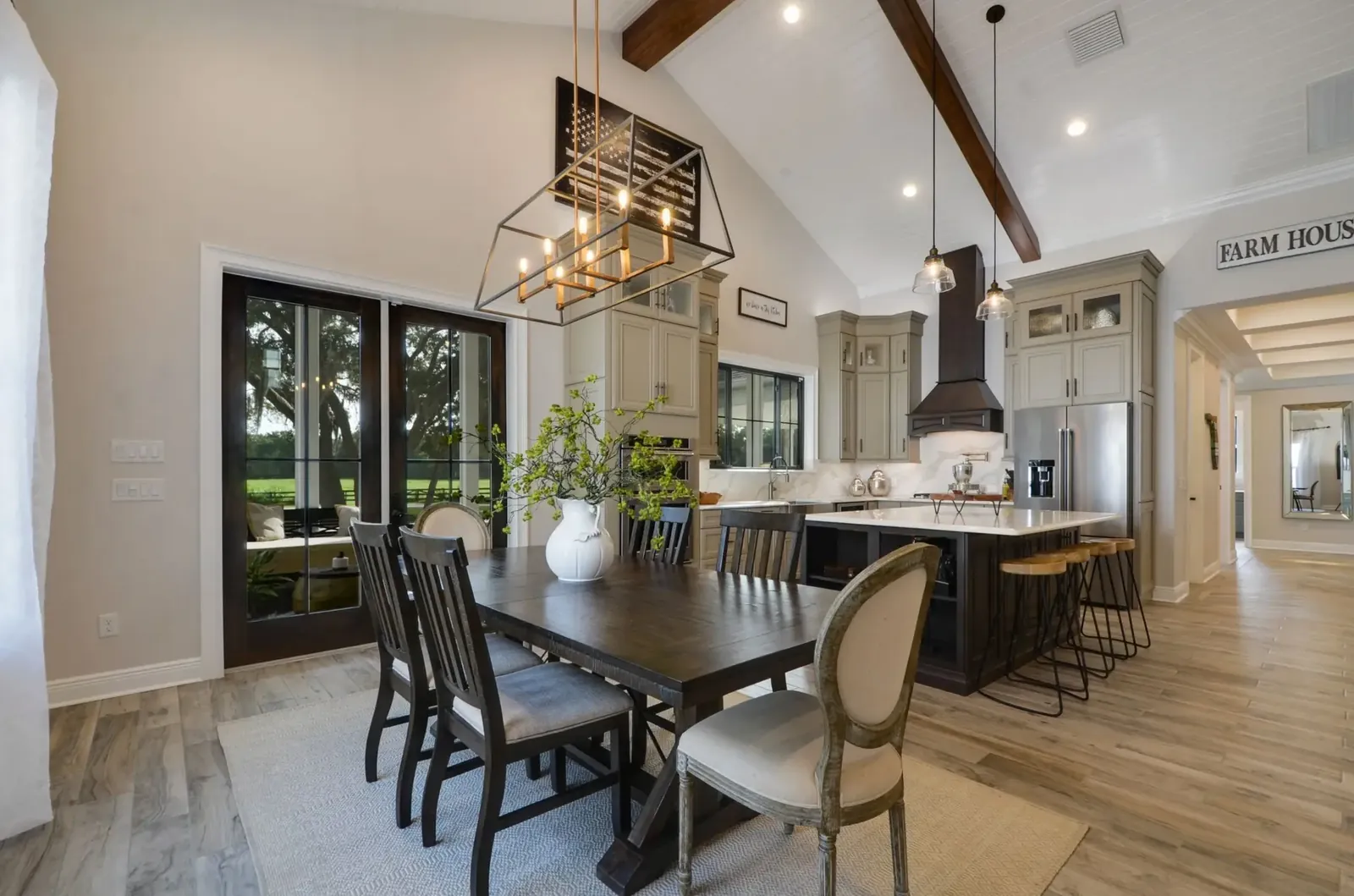 Dining area with a long table, black-framed French doors and a vaulted wood-beam ceiling