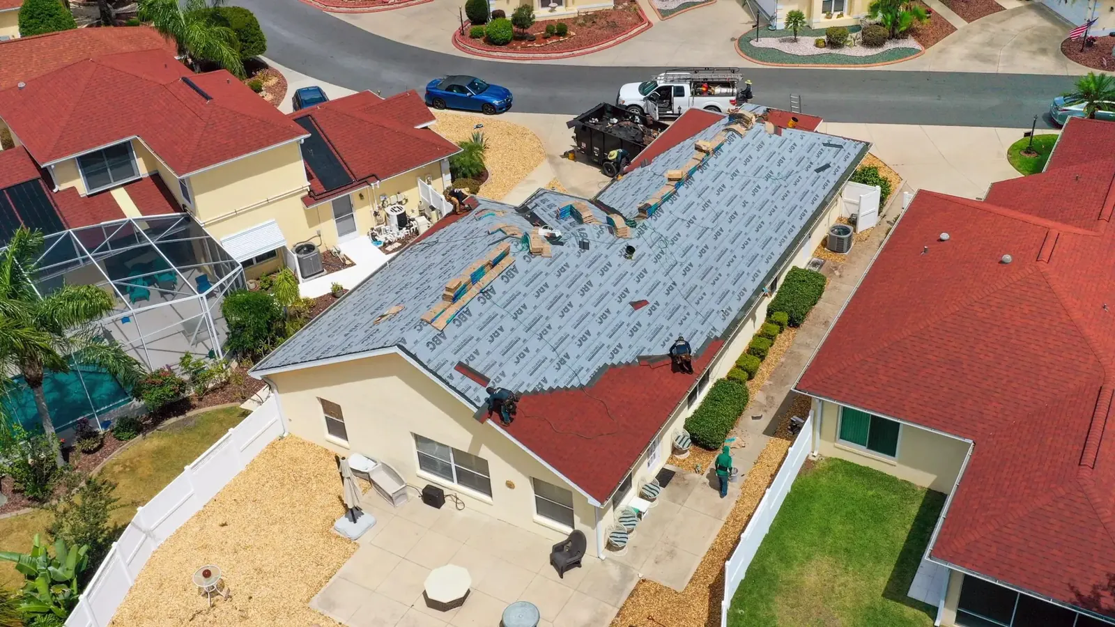 Aerial view of a home with new roof underlayment installed and a work truck parked nearby